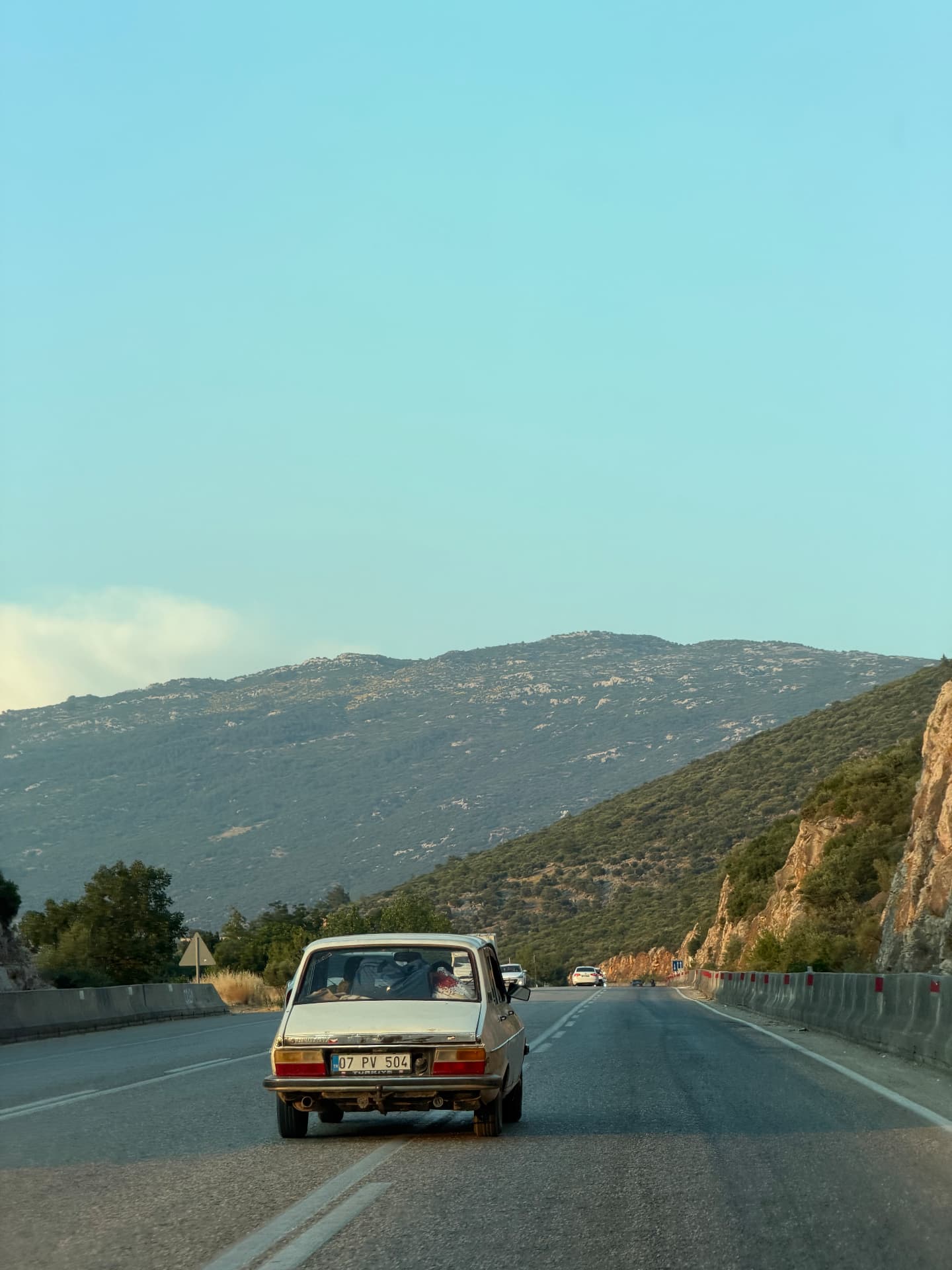 An old white car on a mountain road