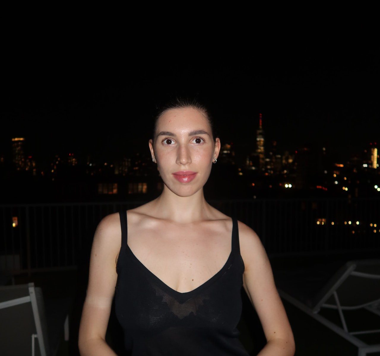 Portrait of Vera Kulakova at night with the city skyline behind her